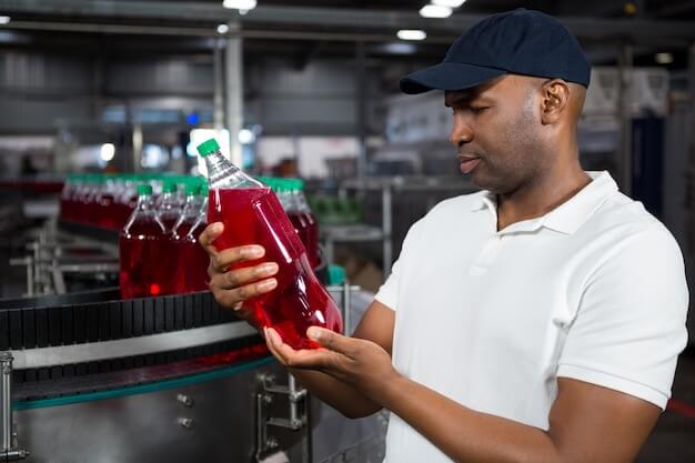 Free photo male worker inspecting juice bottle in factory