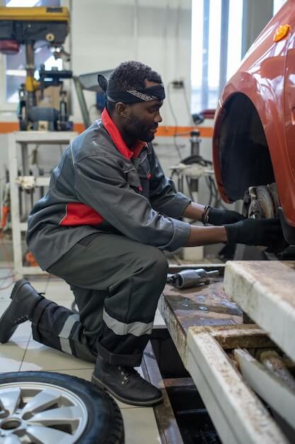 Photo young professional automechanic changing wheel of car