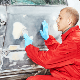 Travailleur Appliquant du mastic sur une carrosserie