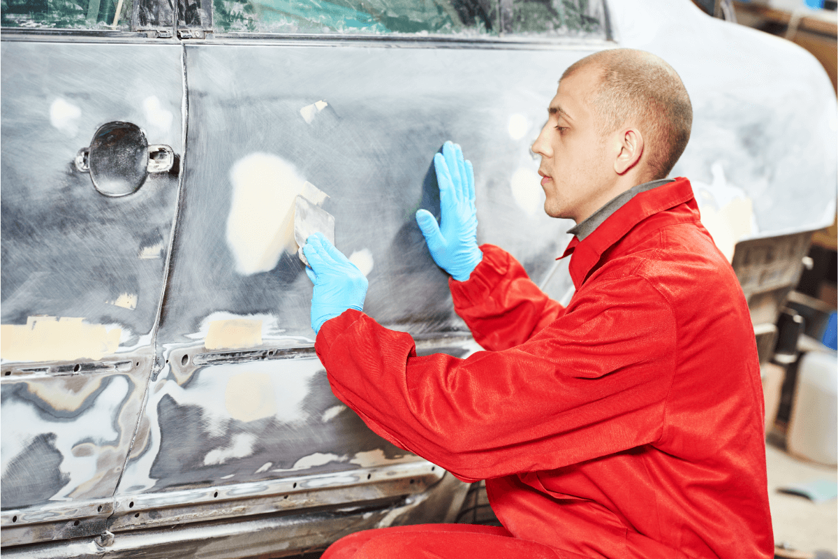 Travailleur Appliquant du mastic sur une carrosserie